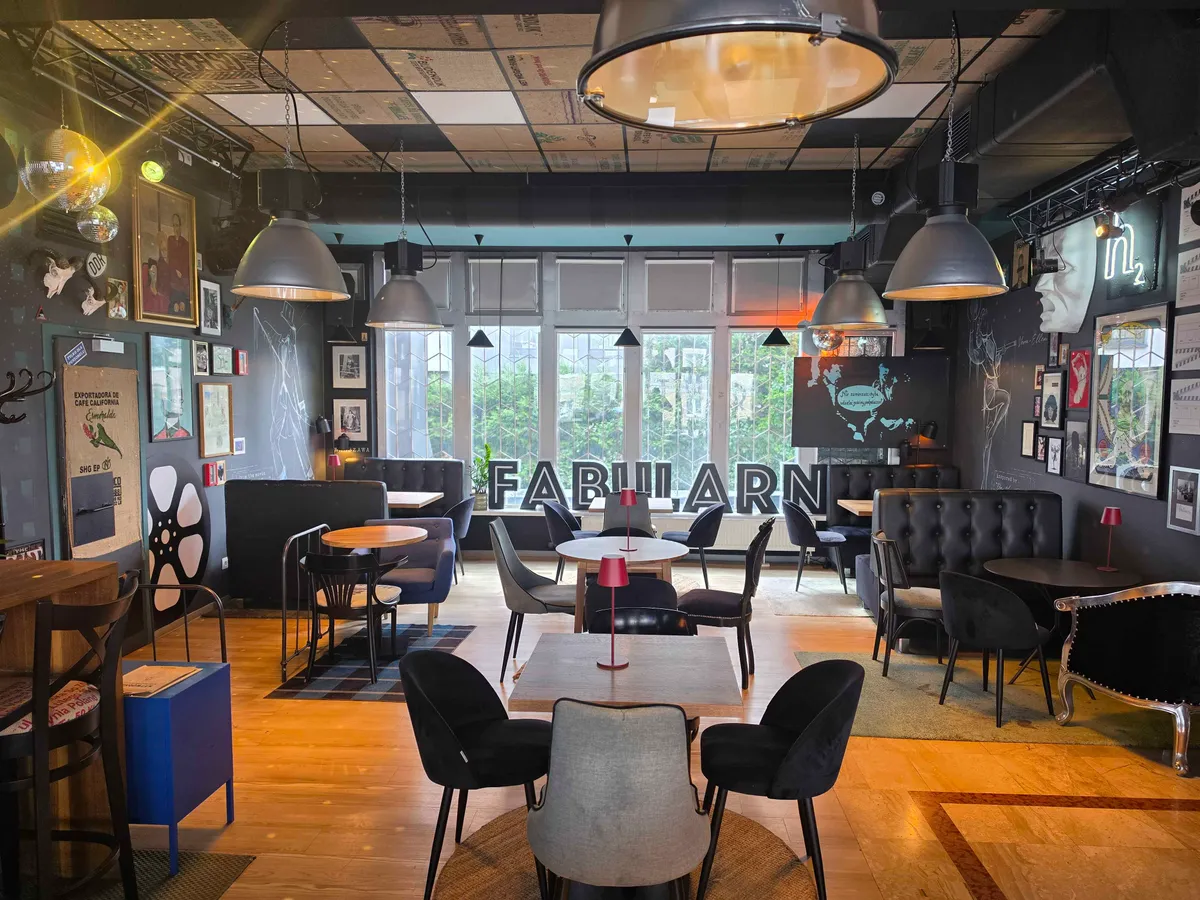 Wnętrze wytwórni BAR: stoliki, fotele i neon „Fabularna” w oknie
