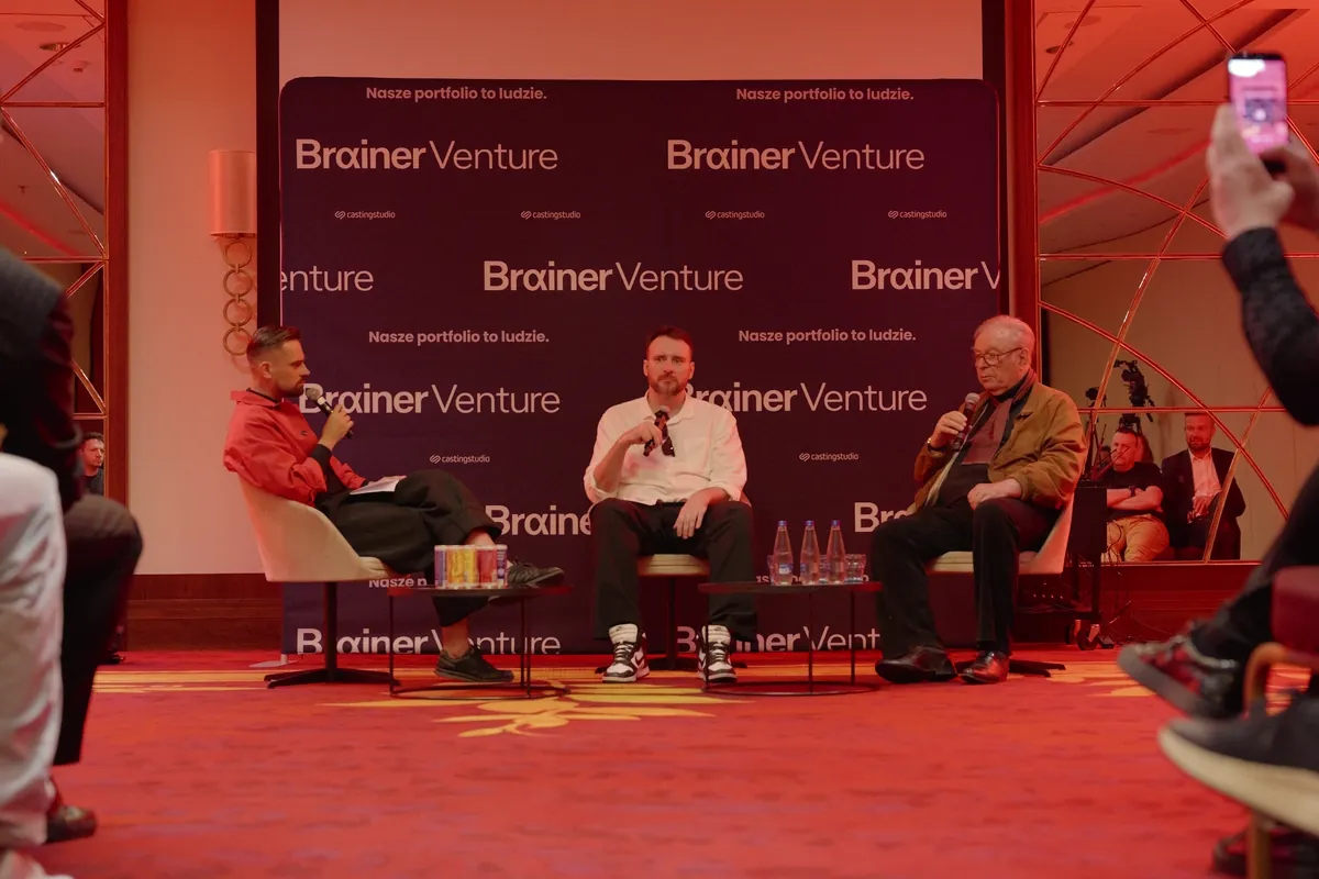 Panel na scenie Warsaw Glitch: trzej rozmówcy z mikrofonami przed ścianką Brainer Venture