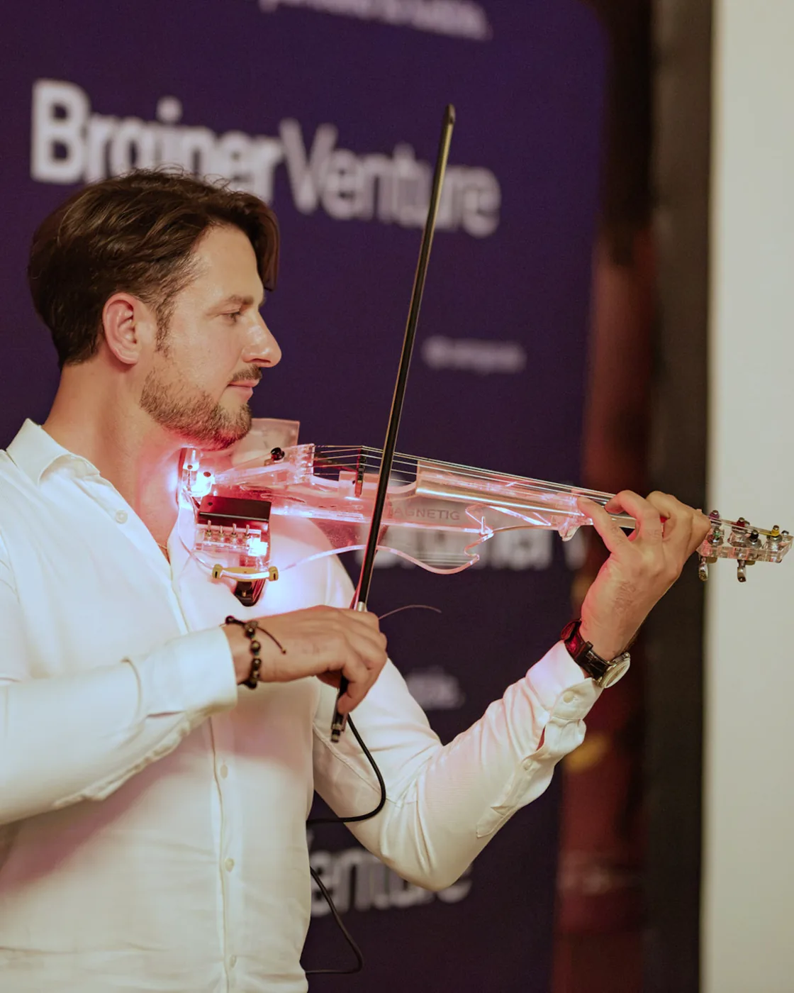Magnetic Violin, pierwszy laureat programu Brainer Venture, gra na podświetlanych skrzypcach przed ścianką Brainer Venture